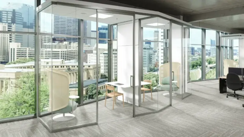 Glass focus pods rendering with high-back lounge chairs on a city-view floor, Anomatics